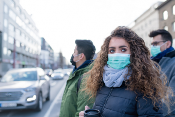 A group of young adults wearing face masks whilst stood outside